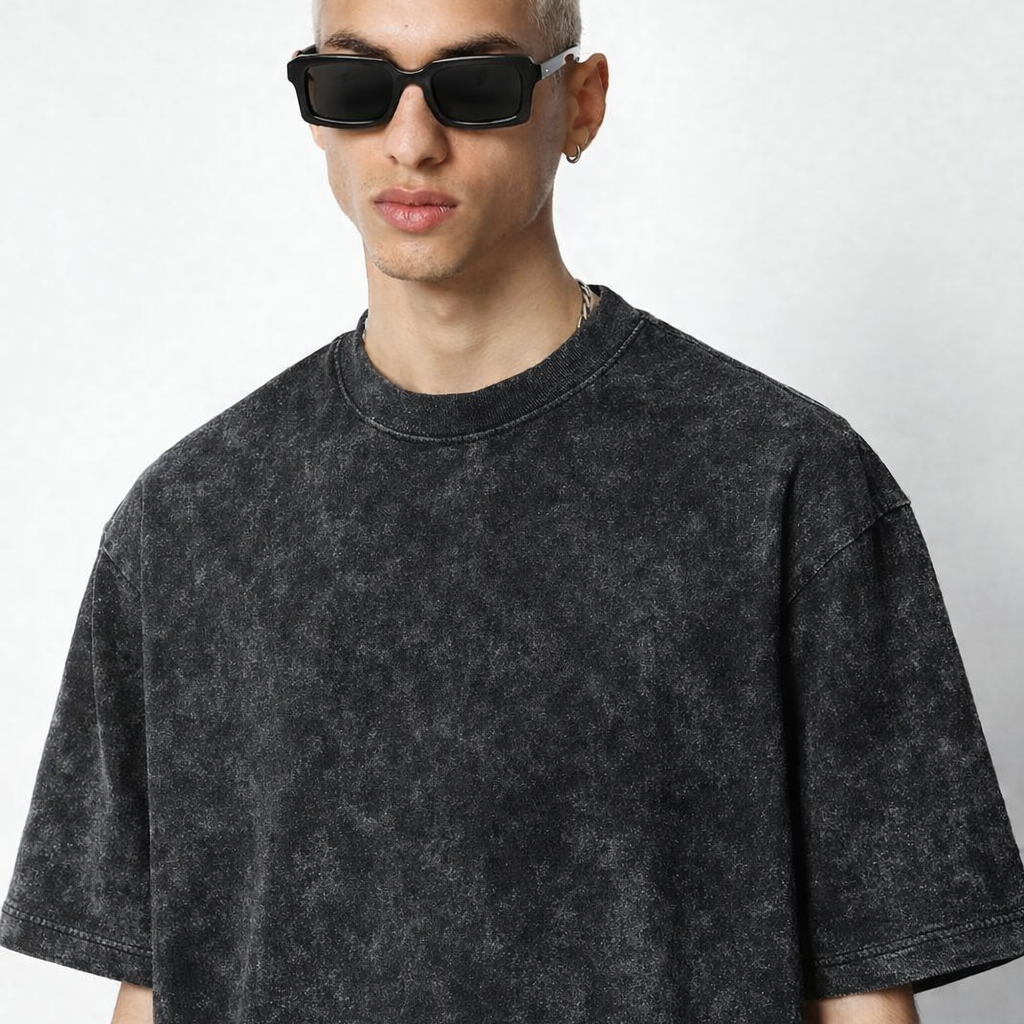 Person wearing a black acid-wash t-shirt and sunglasses on a white background