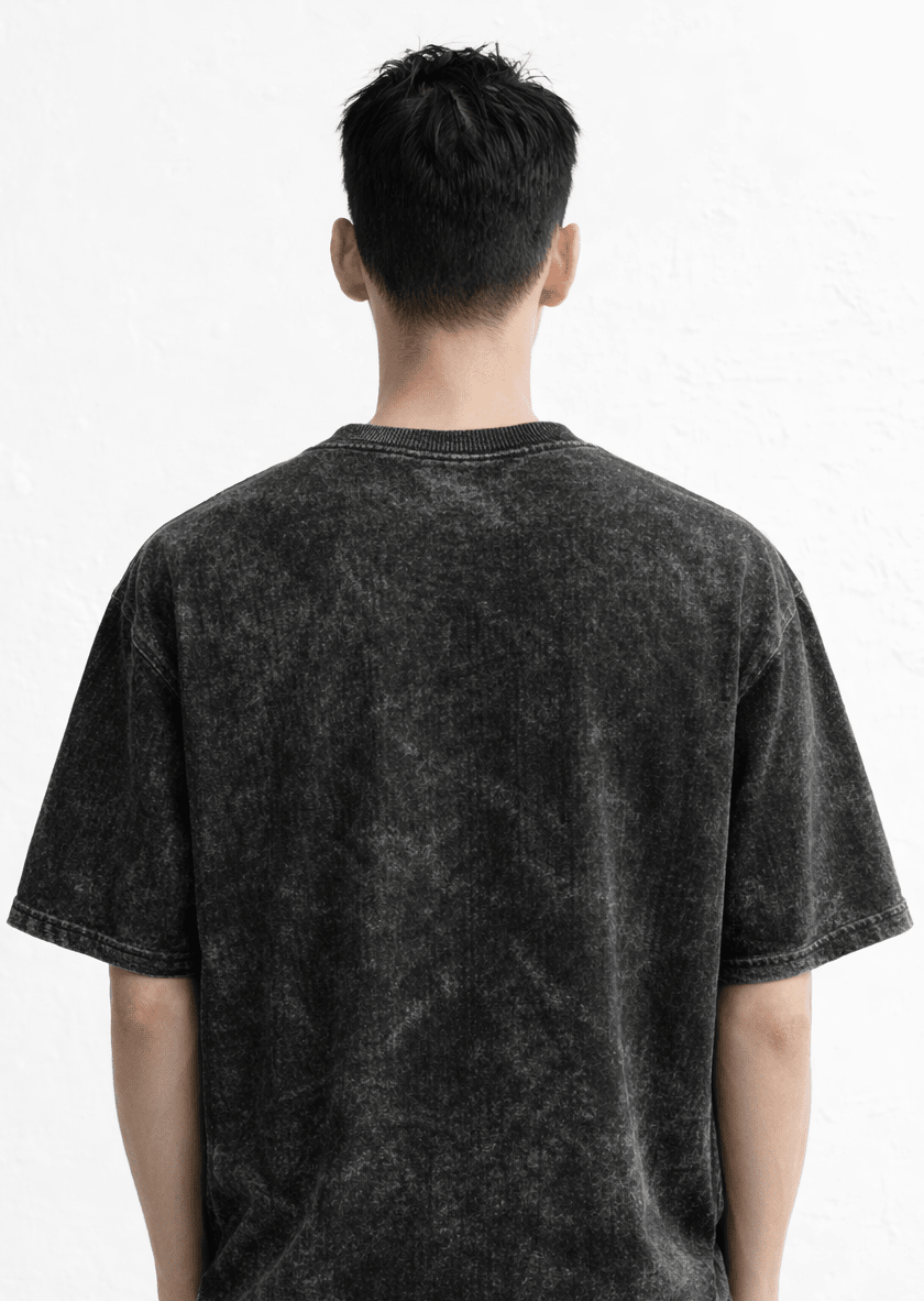 Person wearing a black acid-wash t-shirt and jeans on a white background