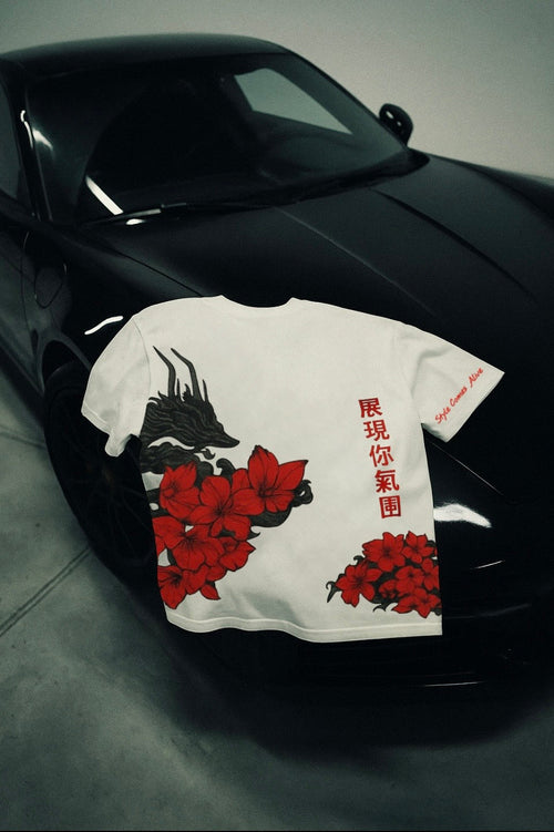 White t-shirt with red and black design on a black car